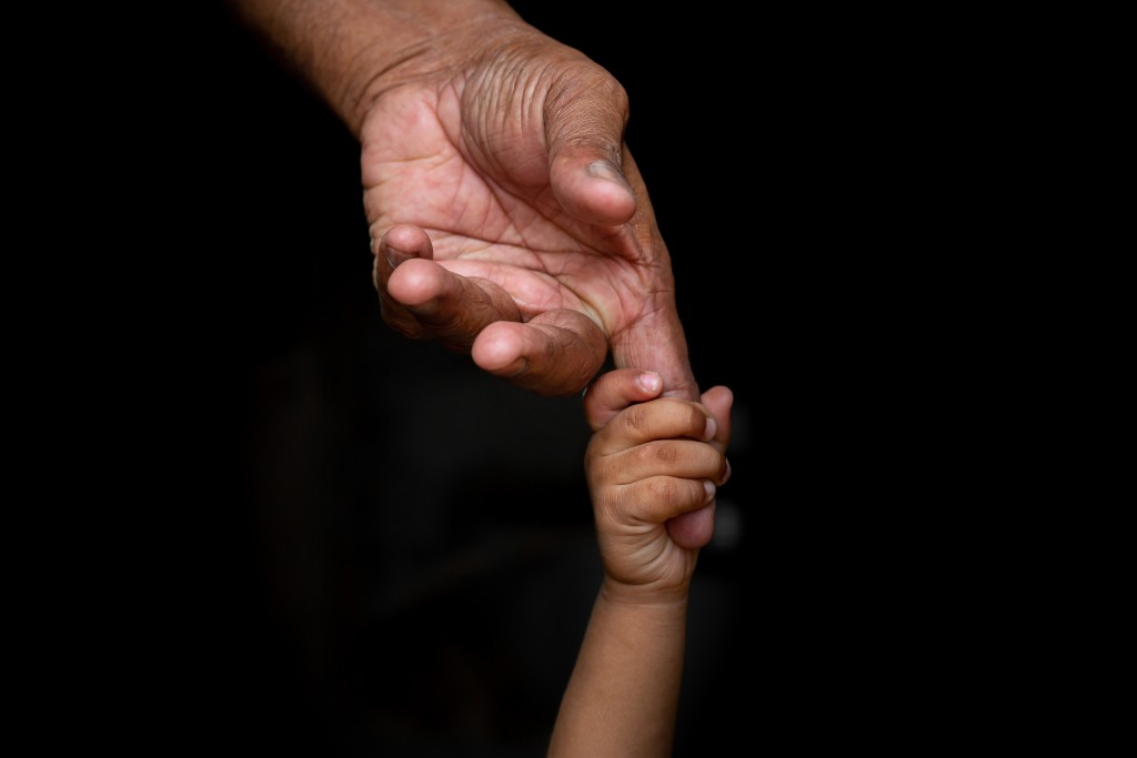 Infant holding adult hand