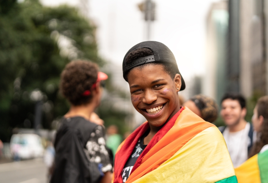 Portrait of young man with rainbow flag with friends on background at Gay Parade LGBTQ youth and suicide risk - What can we do? | Texas Children's Hospital