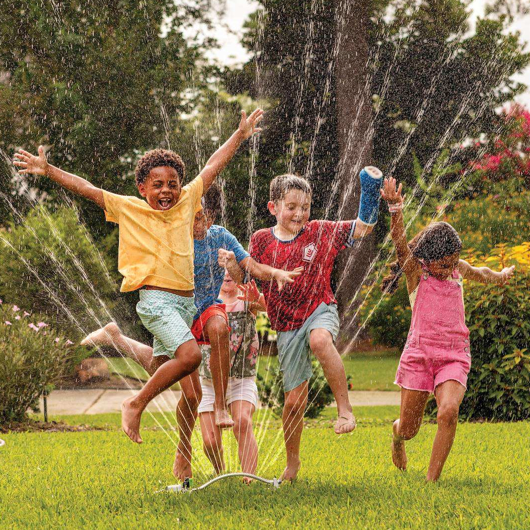 A group of kids playing with a sprinkler in a yard