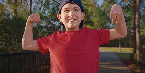 Jonah outside  laughing and flexing his arm muscles 