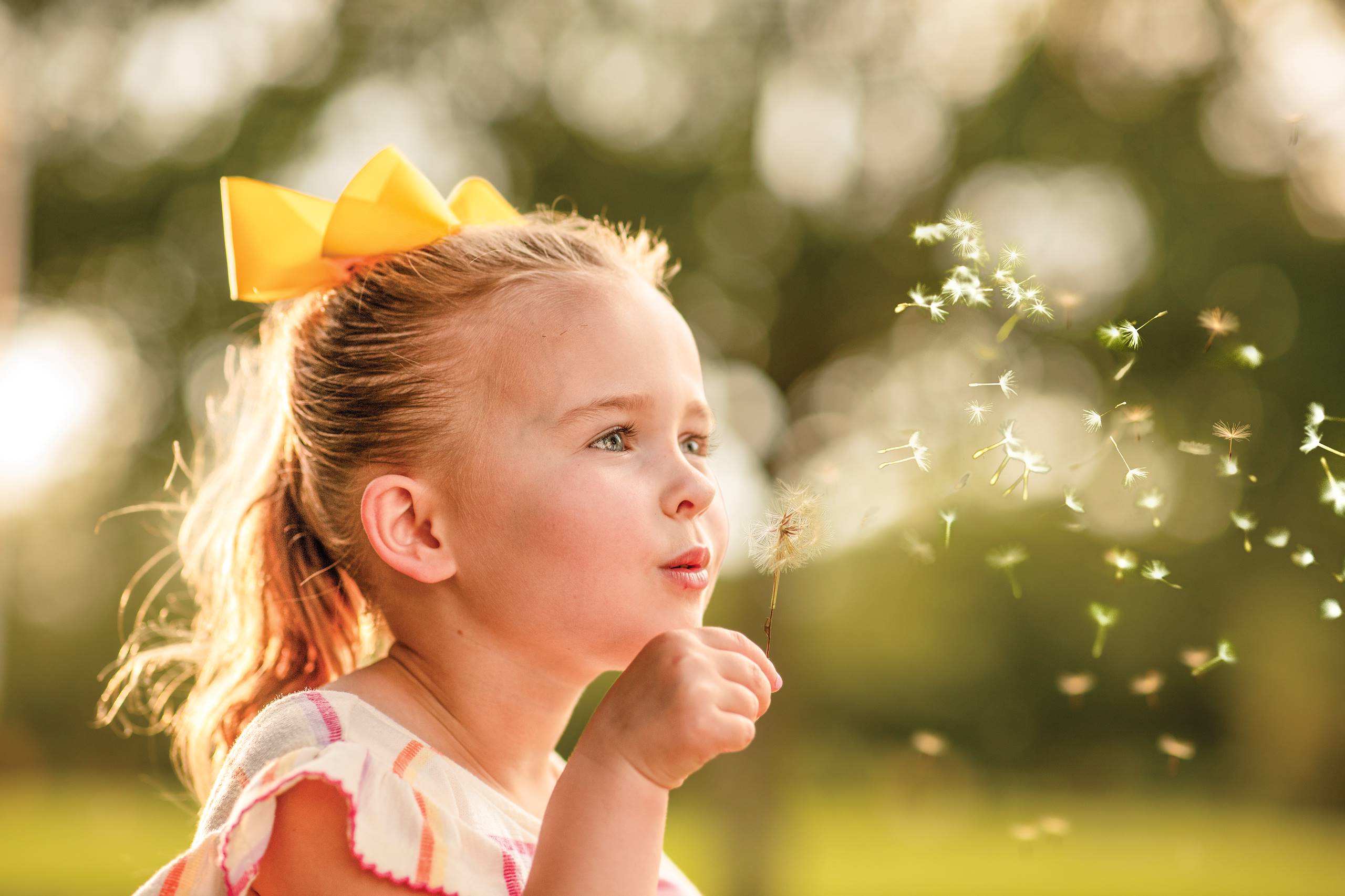 A girl scattering a dandelion flower