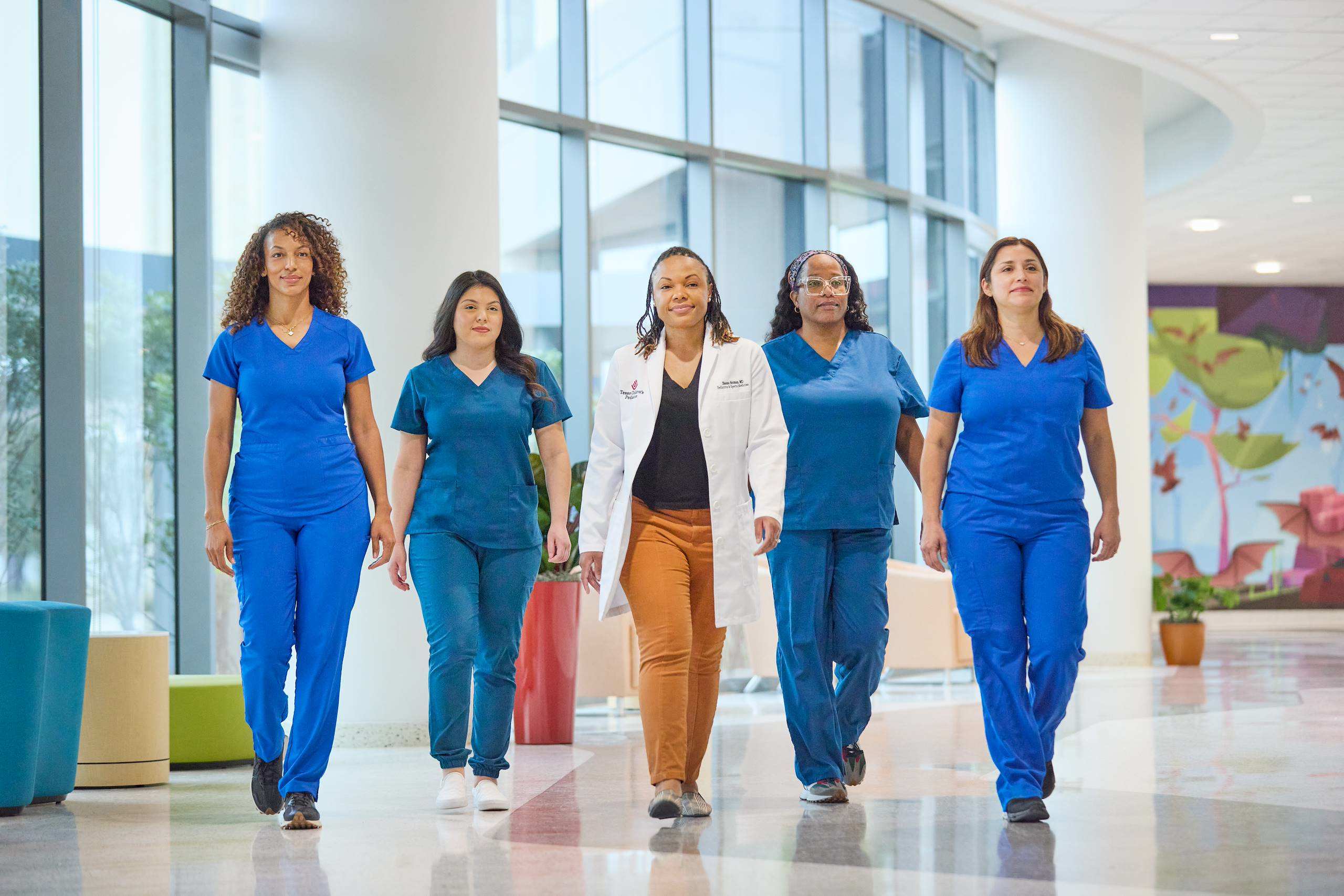 Five doctors walking down a hallway
