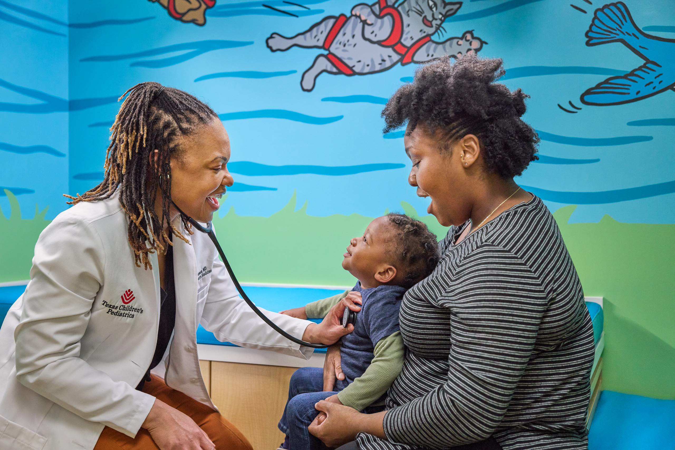 A doctor applying a stethoscope to a child sitting on his mother's lap
