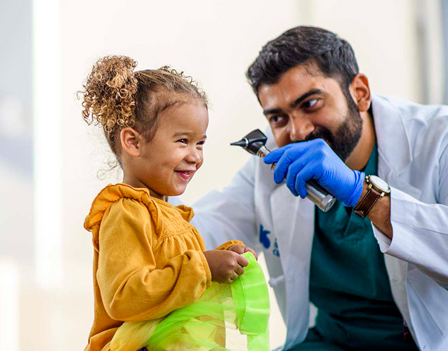 A doctor using an otoscope on a child patient