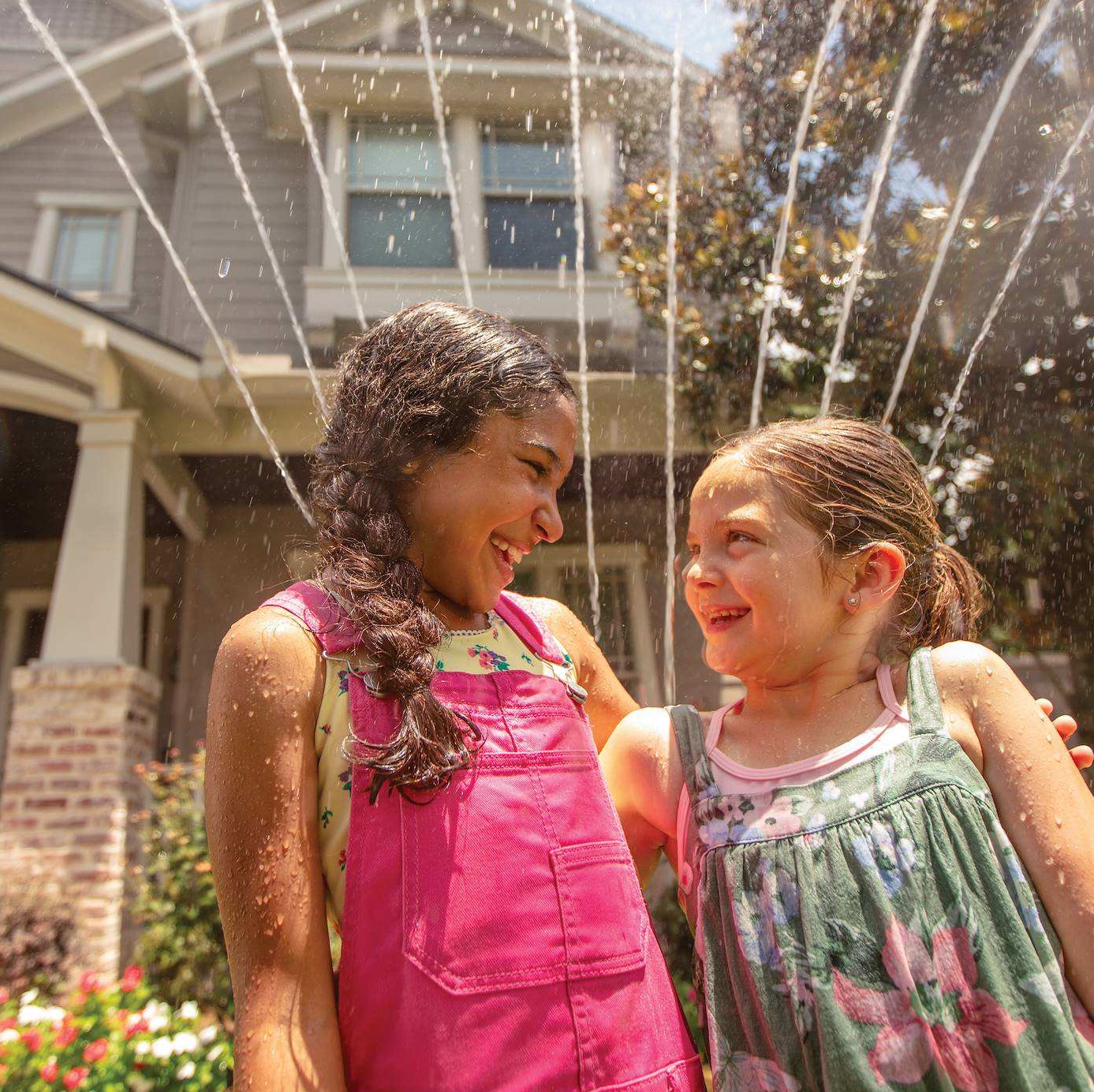 Two girls outside beneath a sprinkler