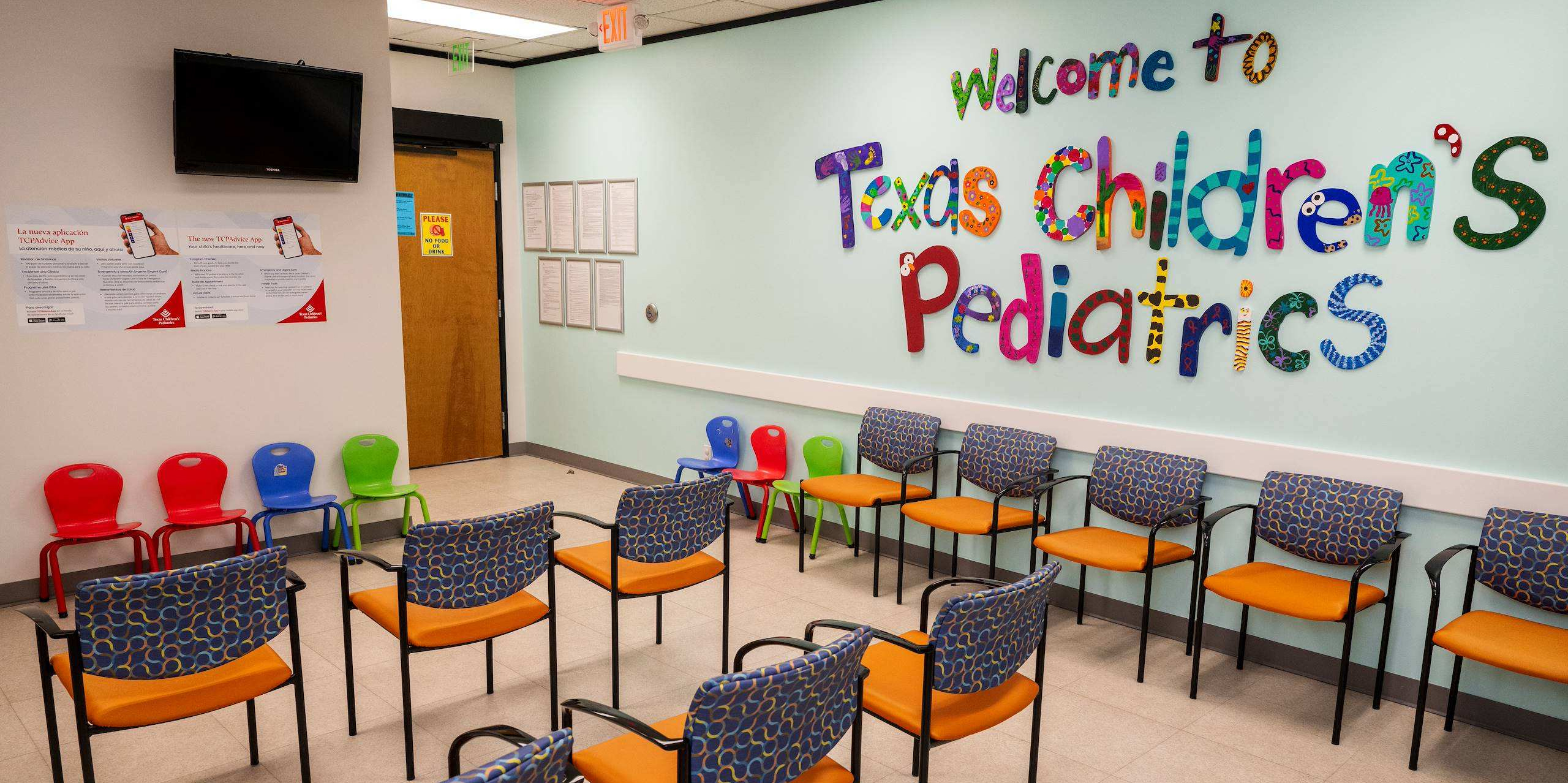 An empty clinic waiting room featuring colorful chairs and a 'Welcome to Texas Children's Pediatrics' wall sign