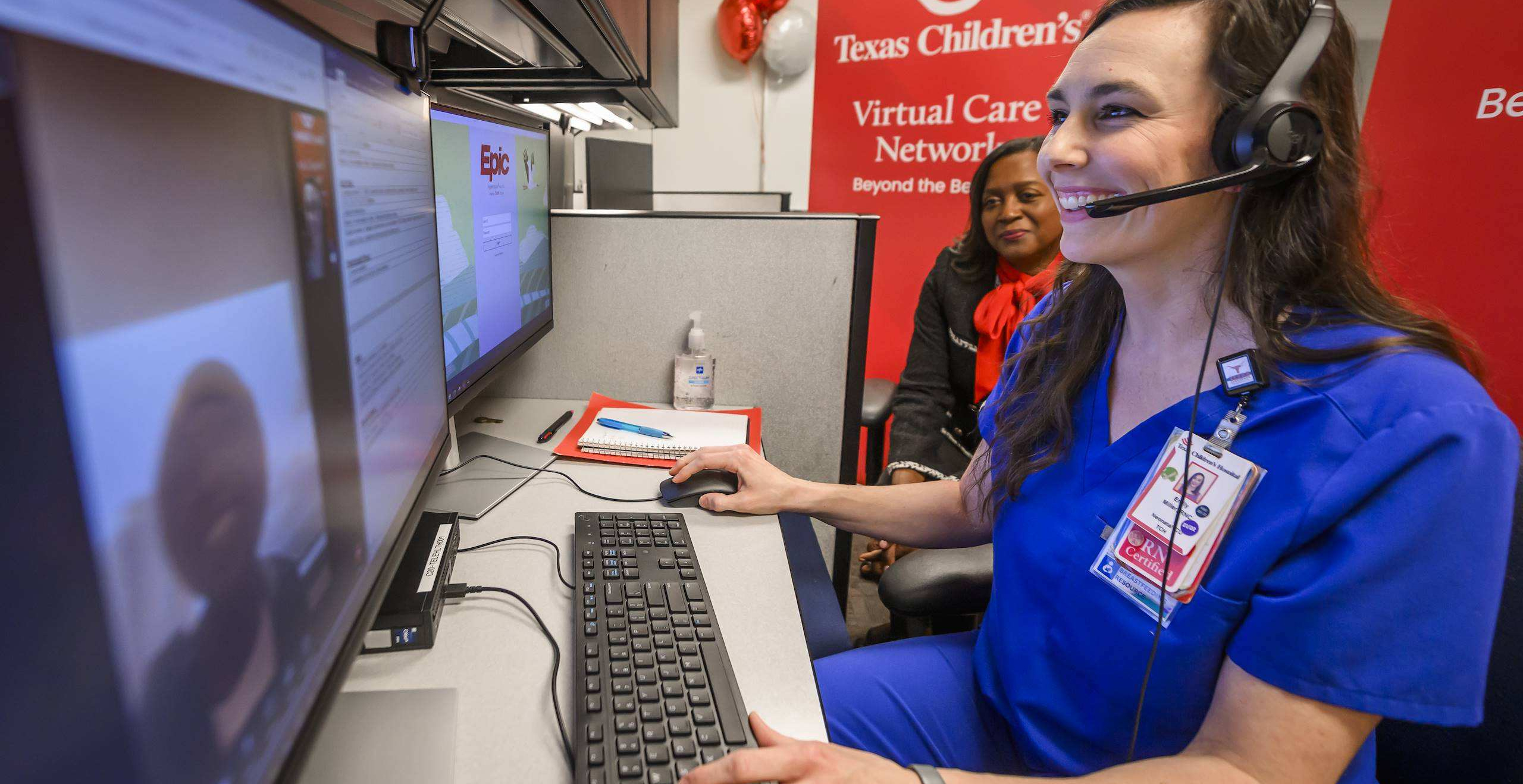 A healthcare provider wearing a headset sitting at a computer desk during a virtual consultation