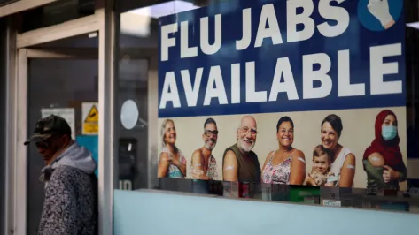A 'Flu Jabs Available' sign displayed at a pharmacy window