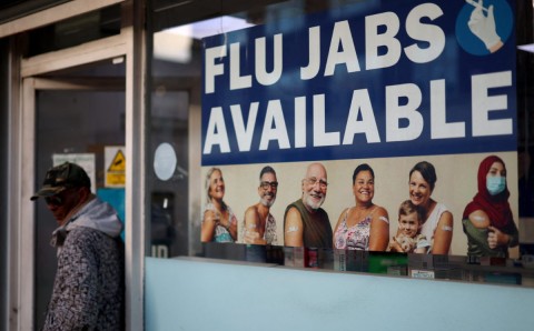 A 'Flu Jabs Available' sign displayed at a pharmacy window